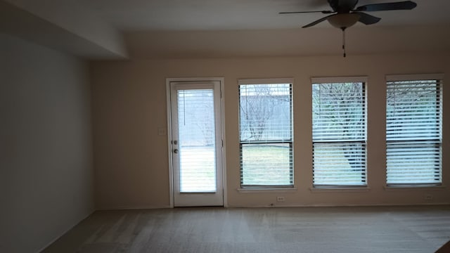 empty room featuring ceiling fan, carpet flooring, and a wealth of natural light