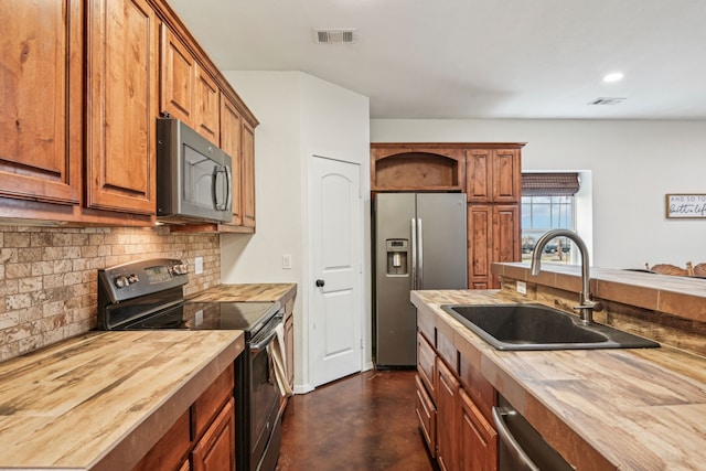 kitchen featuring wood counters, appliances with stainless steel finishes, decorative backsplash, and sink