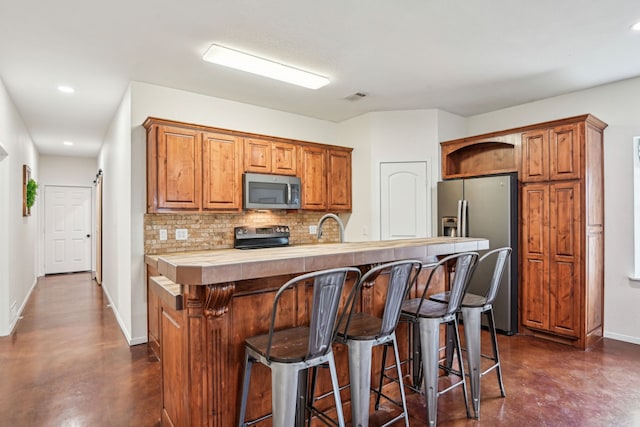 kitchen with sink, decorative backsplash, a barn door, appliances with stainless steel finishes, and a kitchen bar