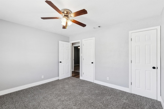 unfurnished bedroom featuring dark colored carpet, visible vents, ceiling fan, and baseboards