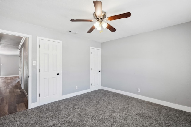 unfurnished bedroom featuring ceiling fan, dark colored carpet, visible vents, and baseboards