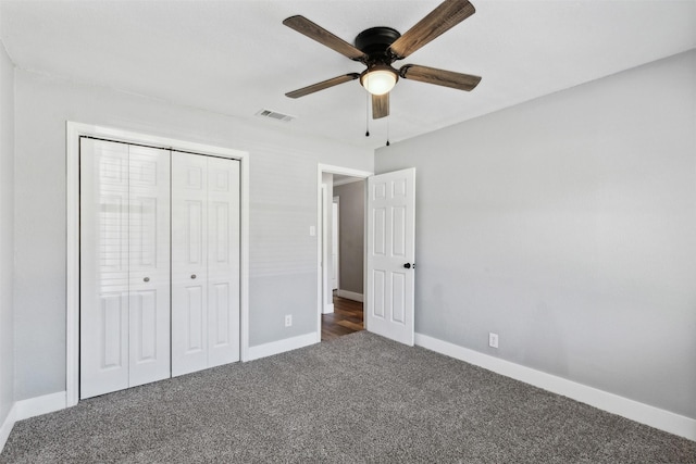 unfurnished bedroom featuring dark colored carpet, a closet, visible vents, a ceiling fan, and baseboards