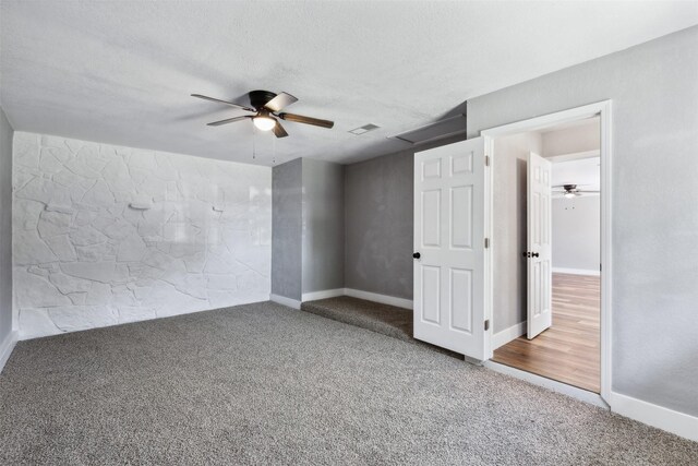 carpeted empty room with ceiling fan and a textured ceiling