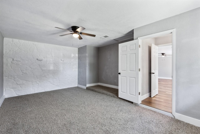 carpeted empty room with a ceiling fan, visible vents, a textured ceiling, and baseboards