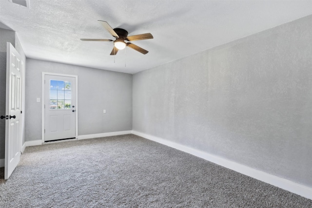 carpeted empty room with a textured ceiling, baseboards, and a ceiling fan