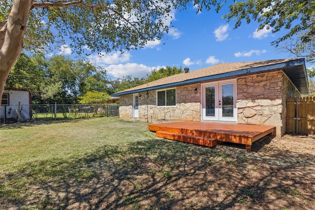 rear view of property with stone siding, a fenced backyard, a wooden deck, and french doors