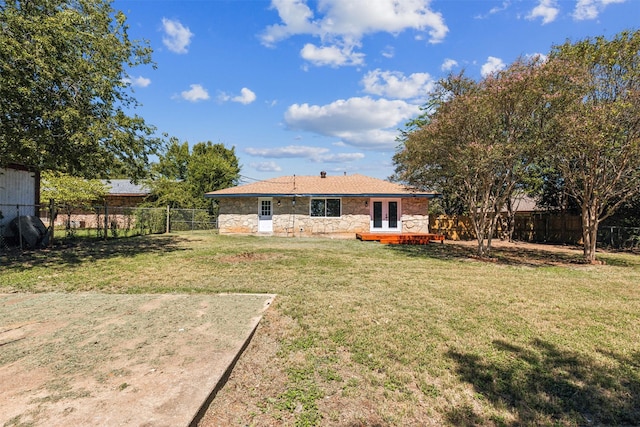 rear view of property featuring french doors and a lawn