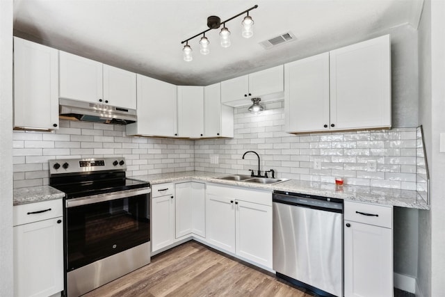 kitchen featuring visible vents, stainless steel appliances, under cabinet range hood, white cabinetry, and a sink