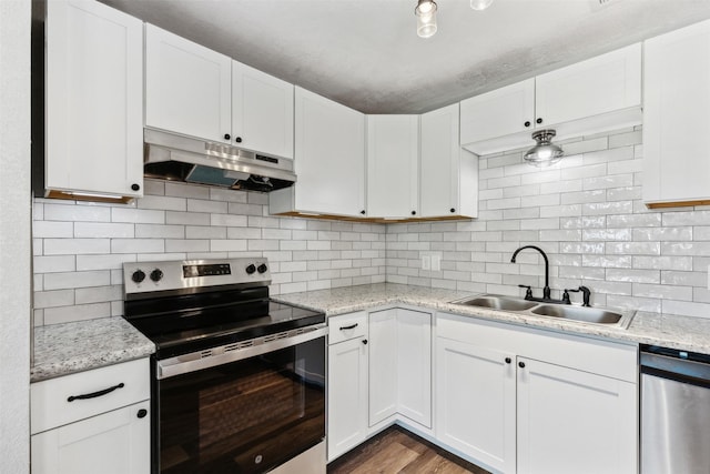 kitchen with under cabinet range hood, stainless steel appliances, a sink, white cabinetry, and backsplash