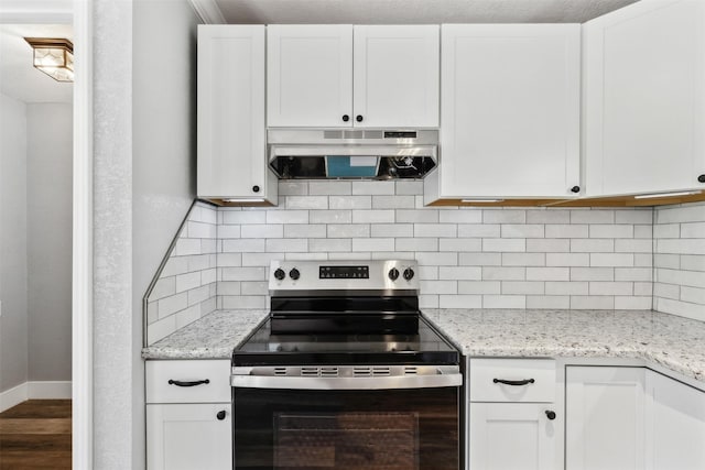 kitchen featuring light stone countertops, backsplash, range hood, white cabinets, and stainless steel electric range