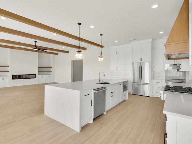 kitchen with white cabinetry, decorative light fixtures, a kitchen island with sink, and appliances with stainless steel finishes