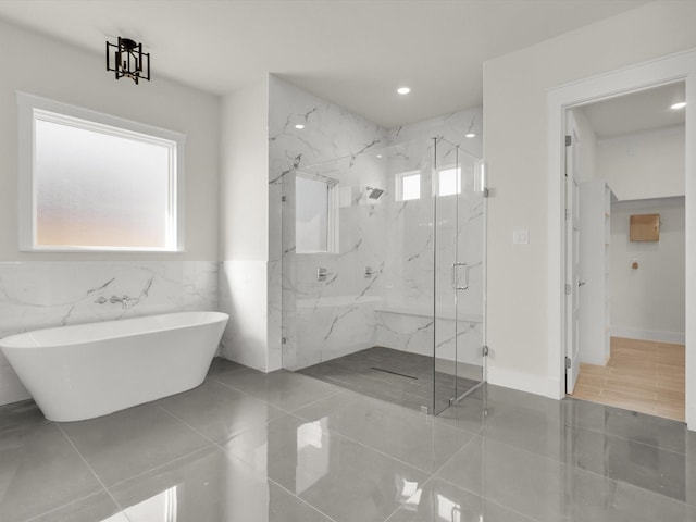 bathroom with tile walls, tile patterned floors, and shower with separate bathtub