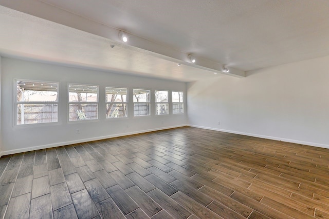 unfurnished room featuring a healthy amount of sunlight and beam ceiling