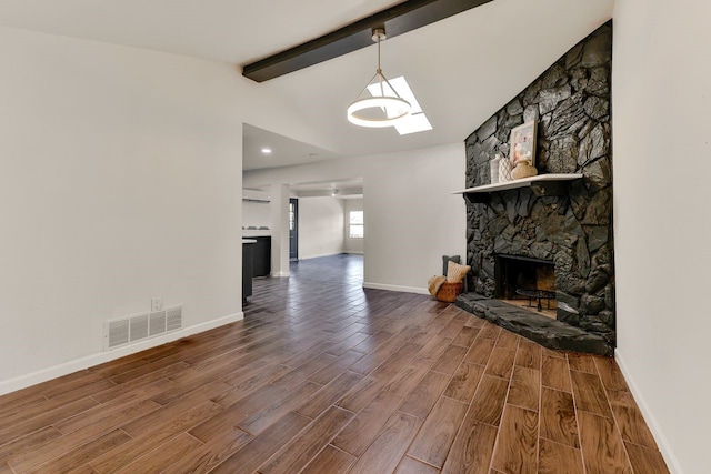 living room featuring a stone fireplace and vaulted ceiling with beams