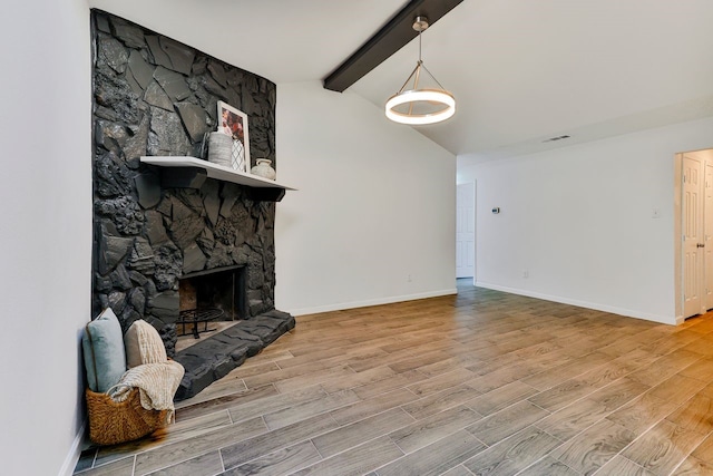 living room with lofted ceiling with beams and a stone fireplace