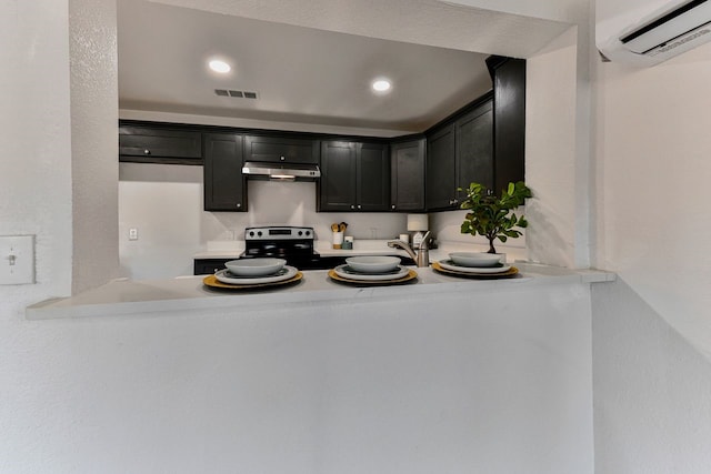 kitchen featuring a wall unit AC and electric stove