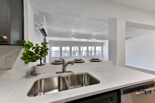 kitchen with sink, stainless steel dishwasher, a wall unit AC, and light stone counters