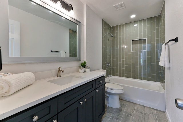 full bathroom featuring toilet, vanity, and tiled shower / bath