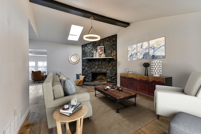 living room featuring wood-type flooring, lofted ceiling with skylight, and a fireplace