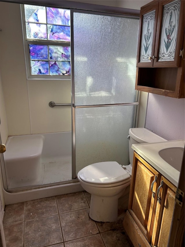 bathroom featuring tile patterned flooring, vanity, walk in shower, and toilet