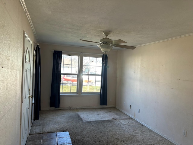 carpeted spare room with ornamental molding, ceiling fan, and a textured ceiling