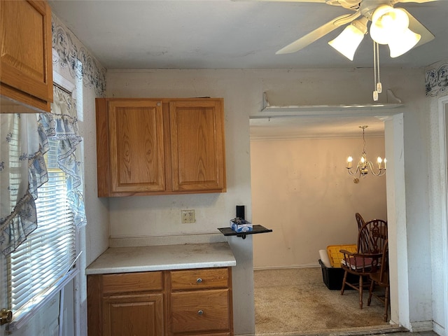 kitchen featuring light carpet, hanging light fixtures, and ceiling fan with notable chandelier