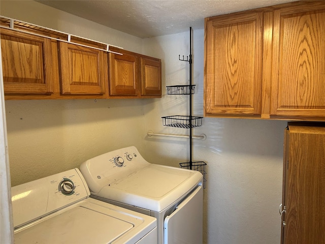 laundry room with cabinets, a textured ceiling, and washer and clothes dryer