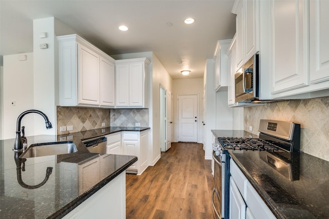 kitchen featuring hardwood / wood-style floors, dark stone counters, sink, appliances with stainless steel finishes, and white cabinetry