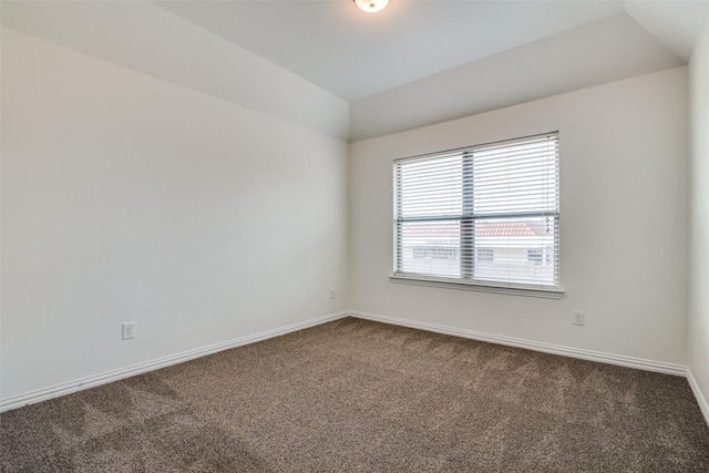 spare room featuring carpet floors and vaulted ceiling