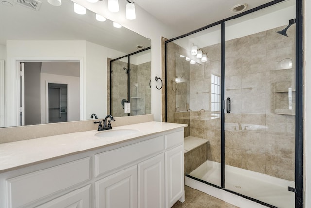 bathroom with tile patterned flooring, vanity, and walk in shower