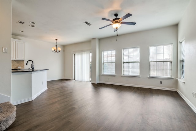 unfurnished living room with dark wood-type flooring and ceiling fan with notable chandelier