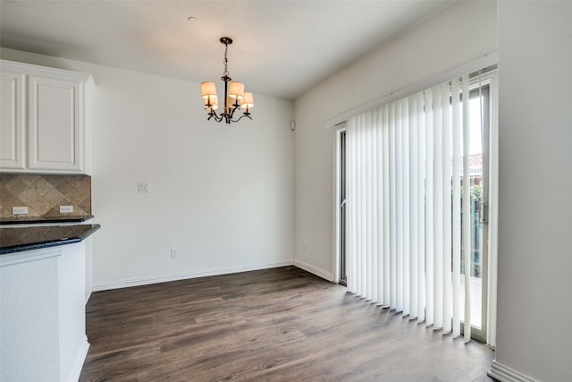 unfurnished dining area featuring dark hardwood / wood-style flooring and an inviting chandelier