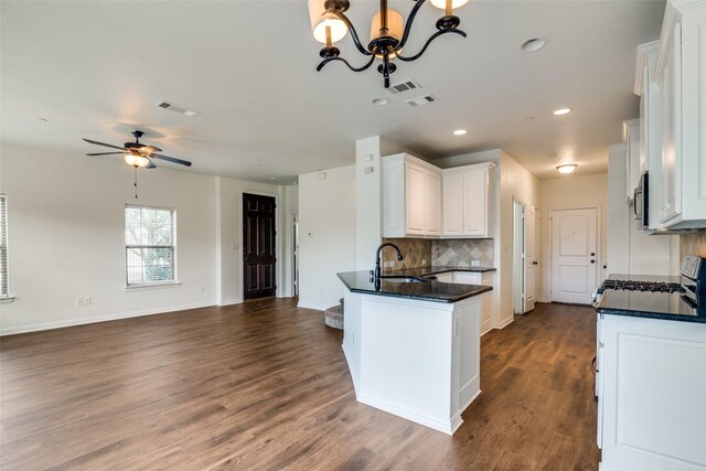 kitchen featuring decorative backsplash, ceiling fan with notable chandelier, dark wood-type flooring, sink, and white cabinets