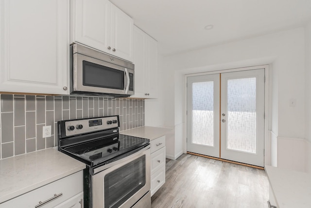 kitchen featuring decorative backsplash, appliances with stainless steel finishes, french doors, light hardwood / wood-style flooring, and white cabinetry