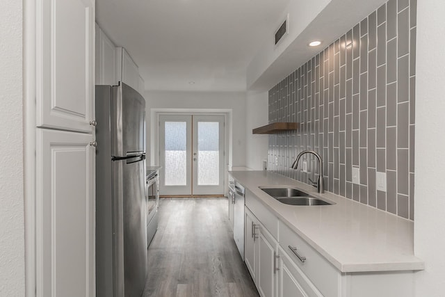 kitchen with white cabinetry, sink, french doors, stainless steel appliances, and backsplash