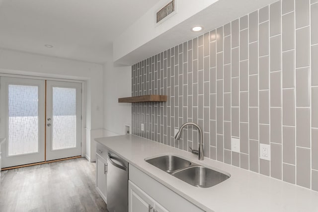 kitchen with dishwasher, backsplash, french doors, white cabinets, and sink