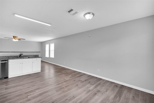 interior space featuring white cabinets, sink, stainless steel dishwasher, ceiling fan, and wood-type flooring