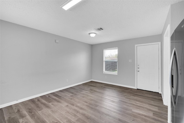 spare room featuring wood-type flooring and a textured ceiling