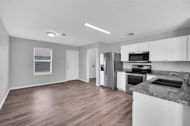 kitchen with sink, dark stone countertops, a textured ceiling, appliances with stainless steel finishes, and white cabinetry