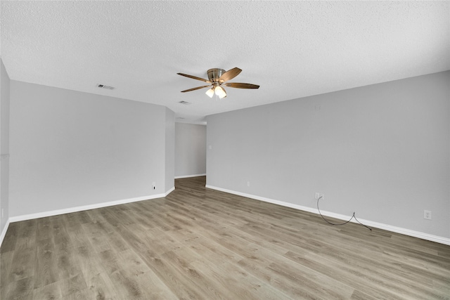 empty room with a textured ceiling, light wood-type flooring, and ceiling fan