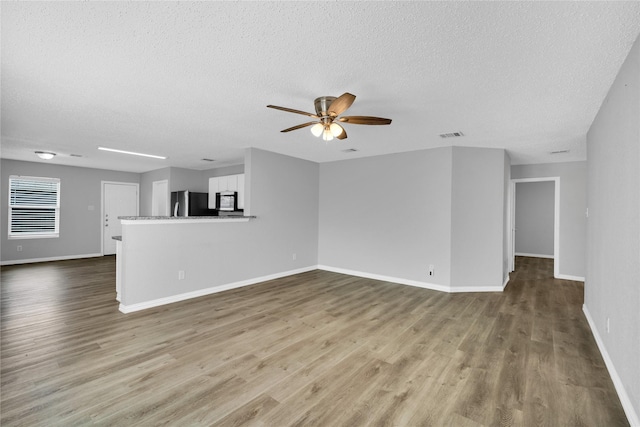 unfurnished living room featuring a textured ceiling, hardwood / wood-style flooring, and ceiling fan