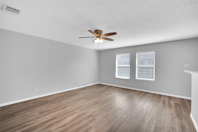 empty room with ceiling fan, wood-type flooring, and a textured ceiling