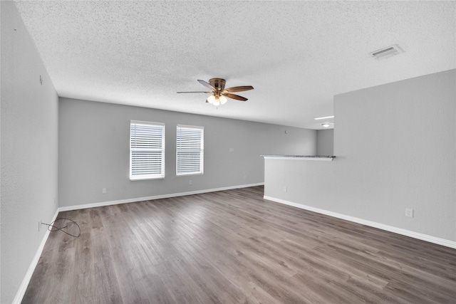 empty room with a textured ceiling, ceiling fan, and dark wood-type flooring