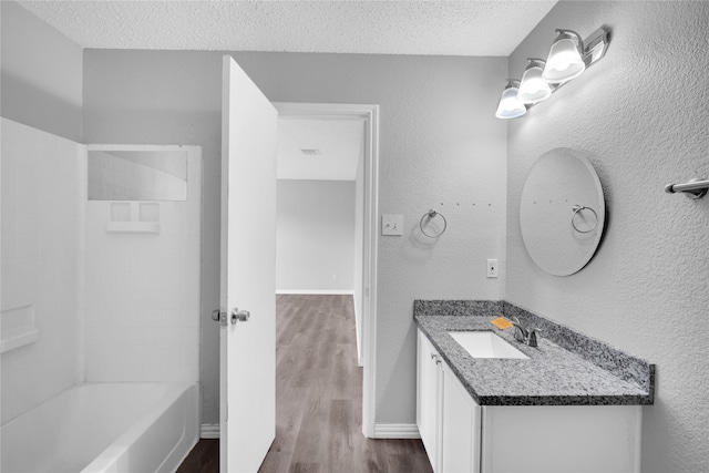 bathroom with vanity, hardwood / wood-style floors, a textured ceiling, and shower / tub combination