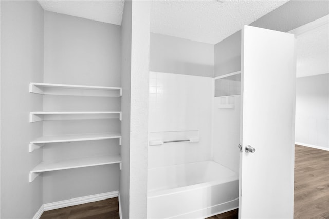 bathroom featuring wood-type flooring, a textured ceiling, and shower / tub combination