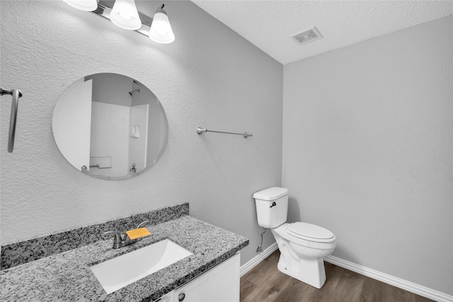 bathroom with vanity, a textured ceiling, hardwood / wood-style flooring, and toilet