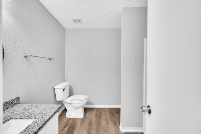 bathroom featuring hardwood / wood-style floors, vanity, a textured ceiling, and toilet