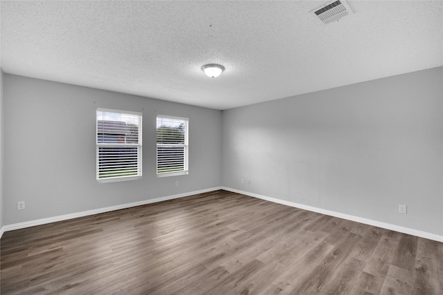 empty room with wood-type flooring and a textured ceiling