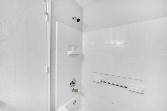 bathroom with a textured ceiling and tub / shower combination