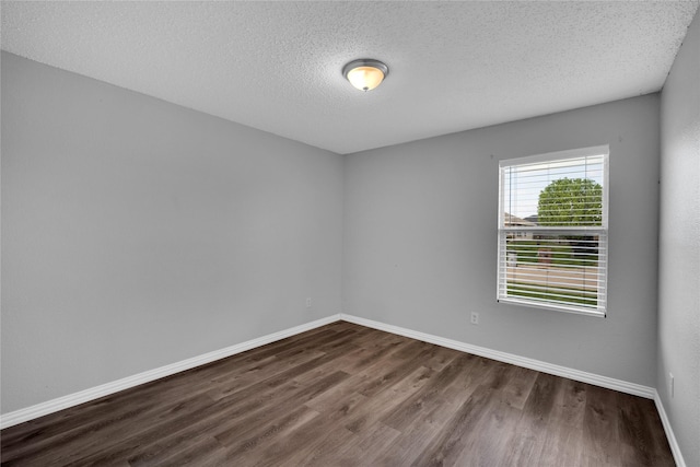 spare room featuring a textured ceiling and dark wood-type flooring